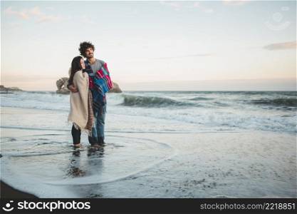 couple with blankets top feet beach water