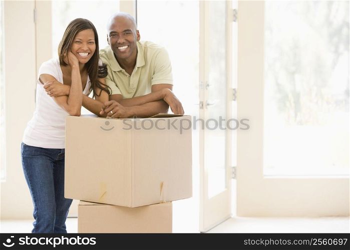 Couple with boxes in new home smiling