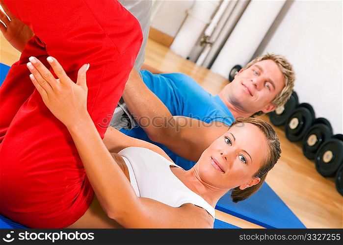 Couple with brightly colored clothes doing sit-ups in the gym