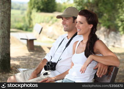 Couple with camera sat on bench