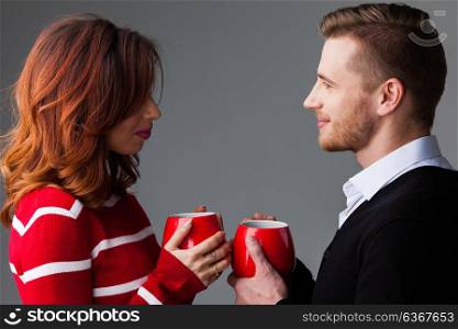 Couple with coffee mags. Young couple holding red coffee mags, Valentine&rsquo;s day concept