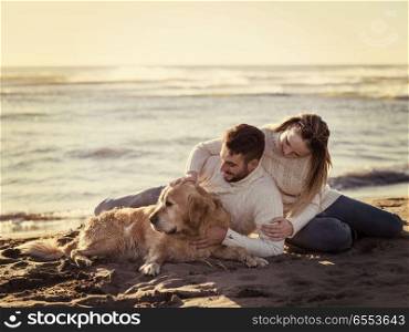 Couple with dog enjoying time on beach. Couple With A Dog enjoying time together On The Beach at autumn day colored filter