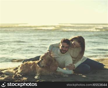 Couple with dog enjoying time on beach. Couple With A Dog enjoying time together On The Beach at autumn day colored filter