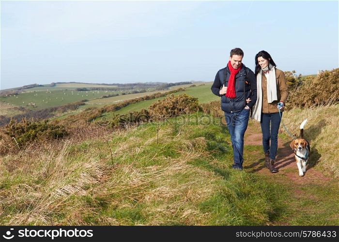 Couple With Dog Walking Along Coastal Path