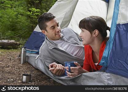 Couple with drinks, lying in tent entrance