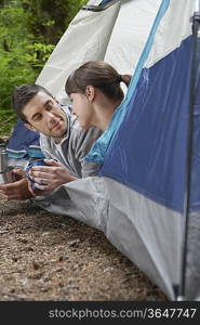 Couple with drinks, lying in tent entrance