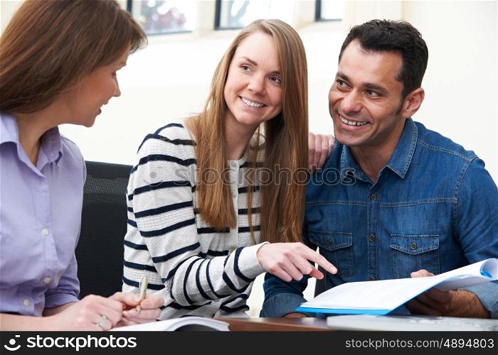 Couple With Financial Advisor Signing Document In Office