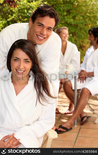 Couple with friends sitting on a terrace in toweling robes