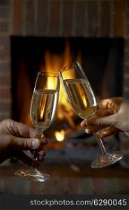Couple With Glass Of Champagne Relaxing By Fire