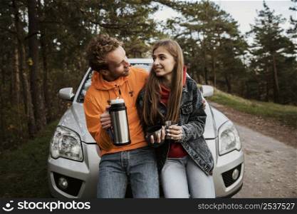 couple with hot beverage while road trip