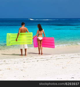 Couple with inflatable rafts on a tropical beach at Maldives