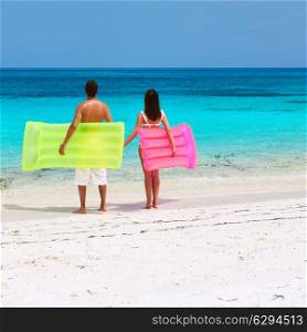 Couple with inflatable rafts on a tropical beach at Maldives