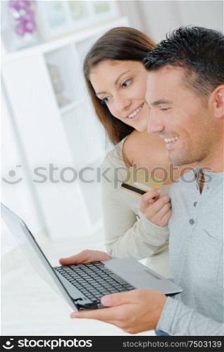 couple with laptop and credit card in living room