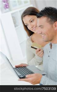 couple with laptop and credit card in living room