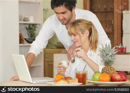 Couple with laptop having breakfast
