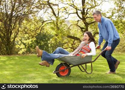 Couple With Man Giving Woman Ride In Wheelbarrow