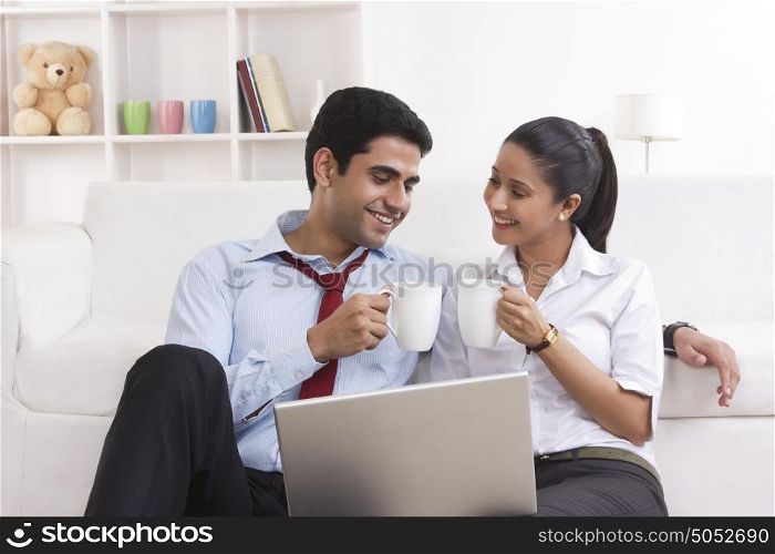 Couple with mug of tea and laptop