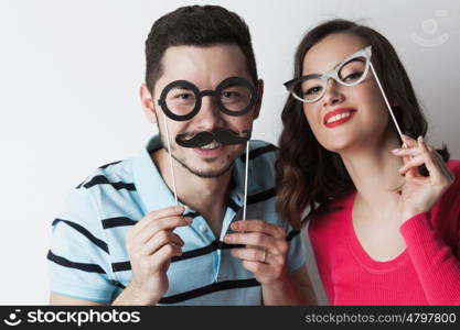 Couple with party glasses and mustaches. Funny couple holding party glasses and mustaches on sticks