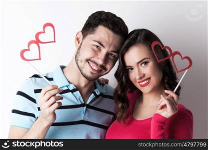 Couple with party heart glasses. Happy smiling couple celebrating Valentine day with funny party heart shaped glasses on stick