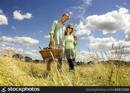 Couple with picnic basket in field
