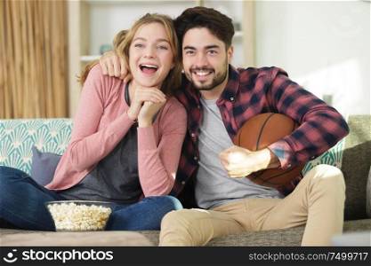 couple with popcorn watching tv sports