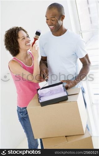 Couple with roller and paint in new home smiling