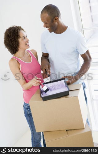 Couple with roller and paint in new home smiling