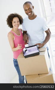 Couple with roller and paint in new home smiling