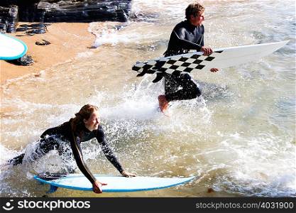 Couple with surfboards splashing