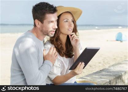 couple with tablet by seaside outdoor