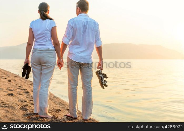 couple with the shoes in his hands near the sea