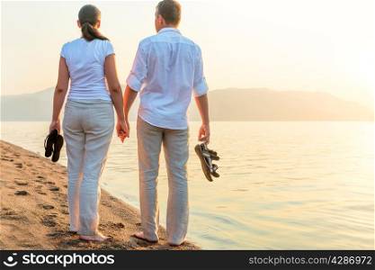 couple with the shoes in his hands near the sea