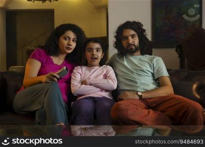 Couple with their daughter watching television in living room