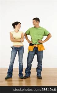 Couple with tools standing and smiling in home.