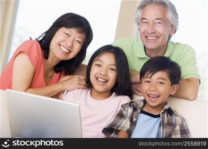 Couple with two young children in living room with laptop smiling