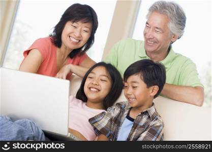 Couple with two young children in living room with laptop smiling