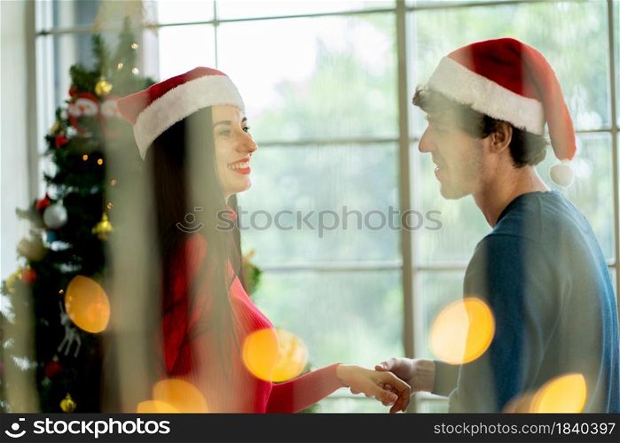 Couple woman and man enjoy with dancing together in Christmas festival with foreground of light bokeh.