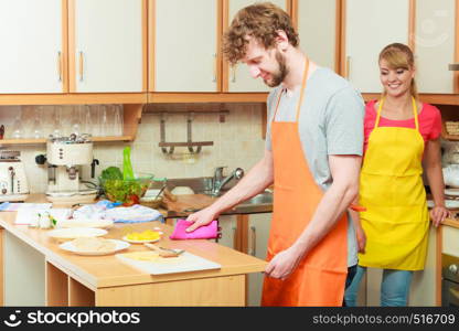 Couple woman and man in apron cooking preparing dinner food in kitchen together.