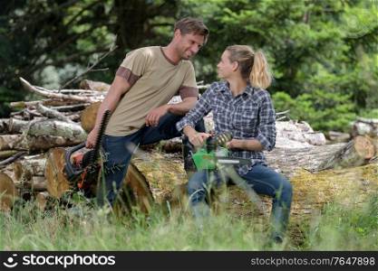 couple working in the woods with chainsaws