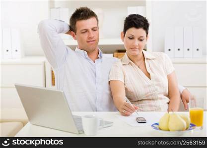 Couple working on laptop computer at home office.