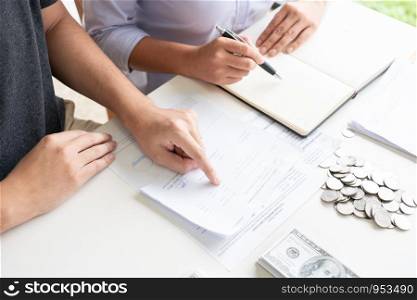 couple working saving account book and calculating her monthly expenses on calculator to calculate financial data, filling in individual income tax return