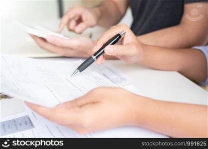 couple working saving account book and calculating her monthly expenses on calculator to calculate financial data, filling in individual income tax return