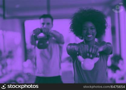 couple workout with weights at crossfit gym. healthy couple workout with weights lifting dumbbels at crossfit gym african american woman with afro hairstyle duo tone filter