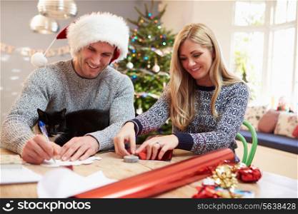 Couple Wrapping Christmas Gifts At Home