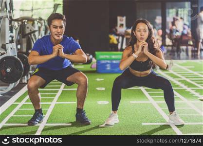 Couple young diversity working out in gym fitness sport complex, doing squad and cardio, posture position, Push up on weights, sports and healthcare,asian and asean people, concept
