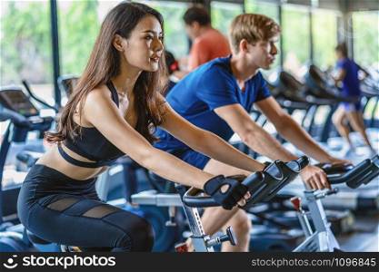Couple young diversity working out in gym fitness sport complex, workout working out bicycle and cardio, posture position, spinning class, sports and healthcare concept