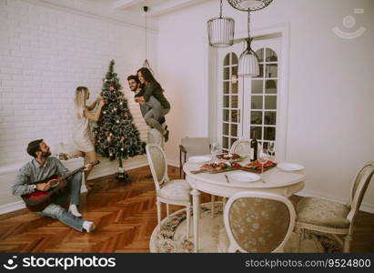 Couples hanging christmas decorations on the tree in the room