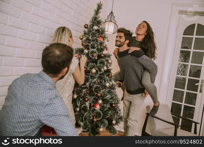 Couples hanging christmas decorations on the tree in the room