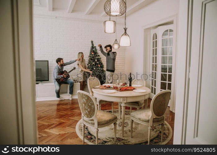 Couples hanging christmas decorations on the tree in the room