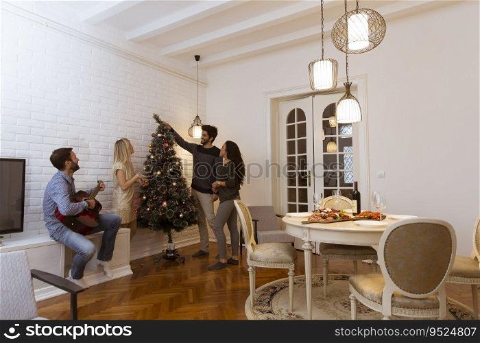 Couples hanging christmas decorations on the tree in the room